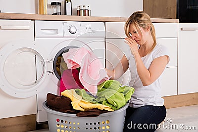 Woman Unloading Smelly Clothes From Washing Machine Stock Photo