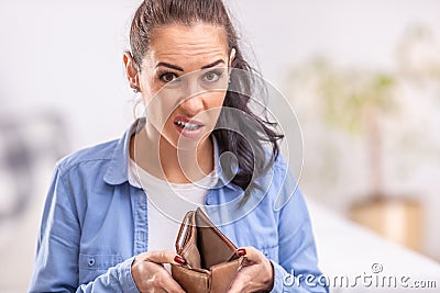 Woman with unsure facial expression holds empty waller or purse open with no money in it Stock Photo