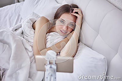 Woman use hands free smartphone holder when lying in bed in bedroom and watching videos or movies. Stock Photo