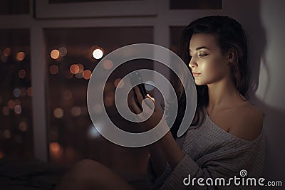 Woman use of mobile phone indoors at night Stock Photo