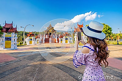 Woman use mobile phone take a photo at Ho kham luang northern thai style in Royal Flora ratchaphruek in Chiang Mai,Thailand. Stock Photo