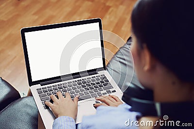 A woman uses an empty laptop screen in a room on a black sofa. Stock Photo