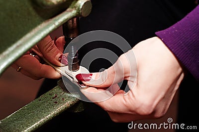 A woman uses a leather riveter to rivet a strip of leather used in the production of handbags / shoes Stock Photo