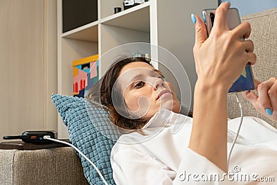 Woman uses a mobile phone, a smartphone, charged from the power bank Stock Photo