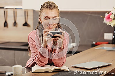 Woman uses phone, laptop for work, leisure, notes pitfalls Stock Photo