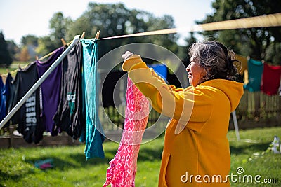 Woman Using Clothe Lines To Dry Clothes In an Energy Efficient Way Stock Photo