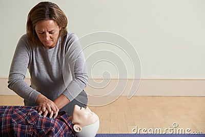 Woman Using CPR Technique On Dummy In First Aid Class Stock Photo