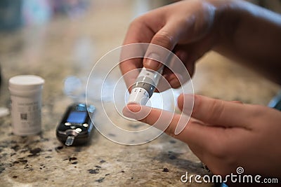Woman using diabetes healthcare blood sugar glucose measurement system at home. Stock Photo