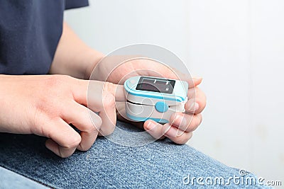 Woman using fingertip pulse oximeter on background, closeup Stock Photo