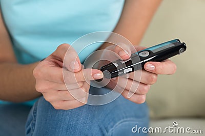 Woman Using Glucometer To Check Blood Sugar Level Stock Photo