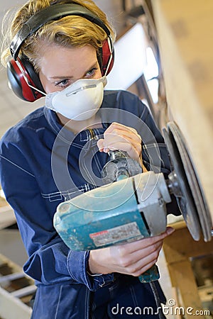 woman using heavy electrical sander and wearing protective equipment Stock Photo