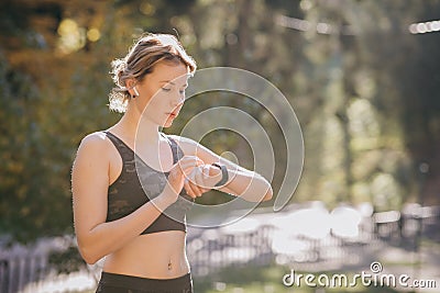 Woman using her smartwatch touchscreen wearable technology device in morning lights Stock Photo