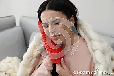 Woman using hot water bottle to relieve pain at home Stock Photo