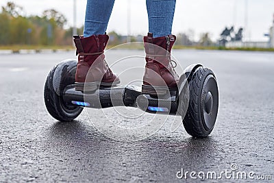 Close up of woman using hoverboard on asphalt road. Feet on electrical scooter outdoor Stock Photo