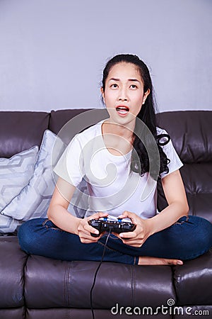 Woman using joystick controller playing video game on sofa in li Stock Photo