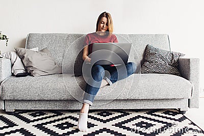Woman using laptop computer sitting on sofa in living room Stock Photo