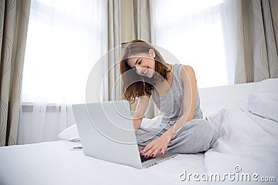 Woman using laptop on hte bed at home Stock Photo