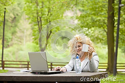 Woman using laptop in park and drinking Stock Photo