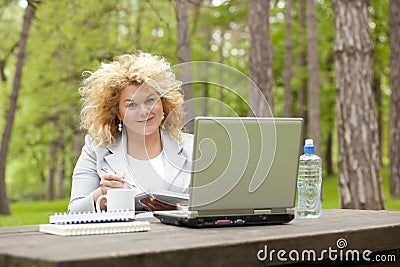 Woman using laptop in park on wooden table Stock Photo