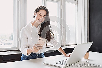 Woman using laptop and smartphone in office. Beautiful girl working at home. Stock Photo