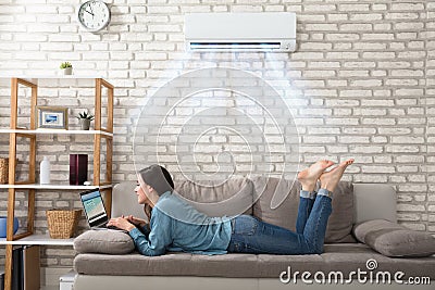 Woman Using Laptop Under The Air Conditioner Stock Photo