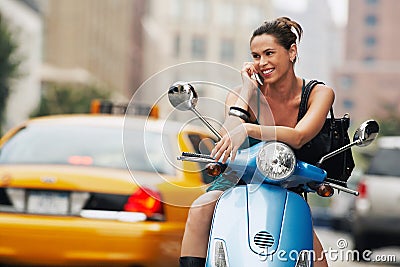 Woman Using Mobile Phone On Moped Stock Photo