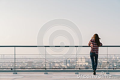 Woman using mobile phone at rooftop during sunset with copy space, communication or lonely people concept Stock Photo