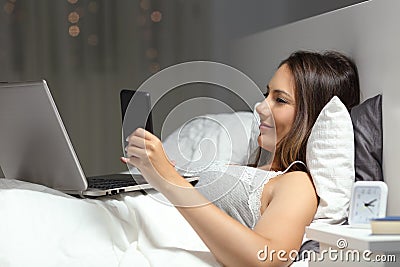 Woman using multiple devices in the night on the bed Stock Photo