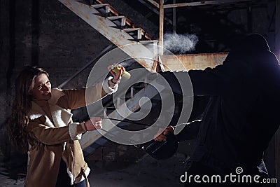 Woman using pepper spray while thief trying to steal her bag outdoors at night. Self defense concept Stock Photo