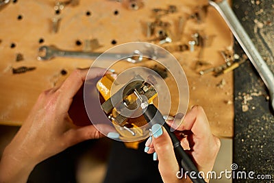 Woman using power working grinder machine, female hand grinds a metal nuts Stock Photo