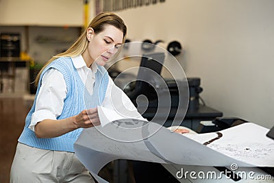 Woman using printer while working in print shop Stock Photo