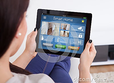 Woman Using Smart Home System On Digital Tablet Stock Photo