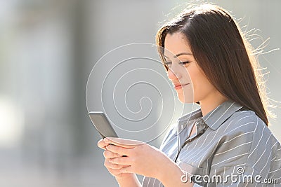 Woman using smart phone in a sunny street Stock Photo