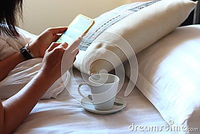 Woman using smartphone on bed Stock Photo