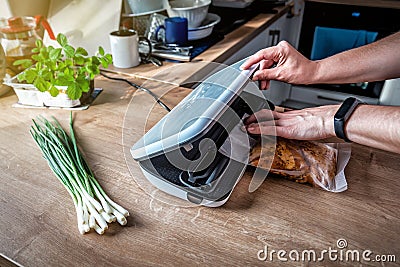 Woman using vacuum seal machine for vacuum packing meat in plastic bags Stock Photo