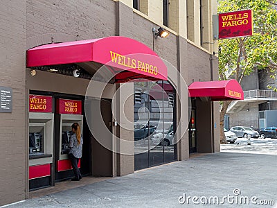 Woman using Wells Fargo ATM machine outside of branch location Editorial Stock Photo
