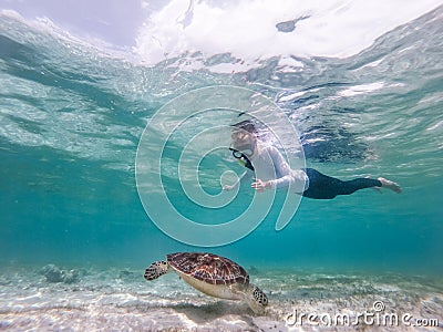 Woman on vacations wearing snokeling mask swimming with sea turtle in turquoise blue water of Gili islands, Indonesia Stock Photo