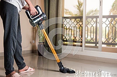 Woman vacuuming the living room with cordless vacuum cleaner Stock Photo