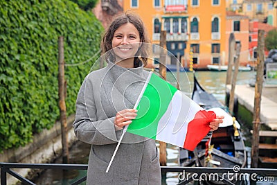 Woman in Venice with italian flag in hands. Girl on gondola in canal background. Happy tourist in Venezia, Italy Stock Photo