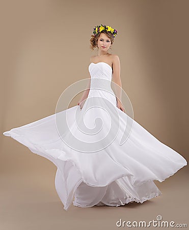 Woman in Vernal Wreath of Flowers in Flying Wedding Dress Stock Photo