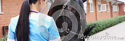 Woman veterinarian feeding horse from hand at ranch Stock Photo