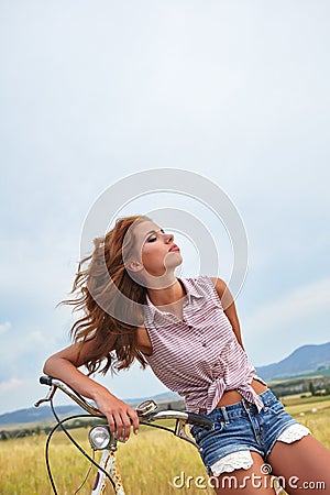 Woman with vintage bike in a country road. Stock Photo