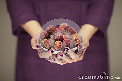 Woman in violett 50`s dress hands holding some lichees Stock Photo