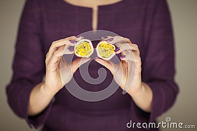 Woman in violett 50`s dress hands holding some passion fruits Stock Photo
