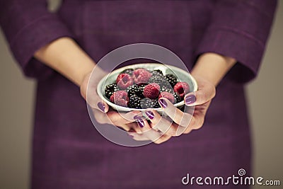 Woman in violett 50`s dress hands holding some raspberries and blackberries Stock Photo