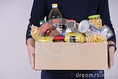 Woman volunteer hands holding food donations box with food grocery products Stock Photo