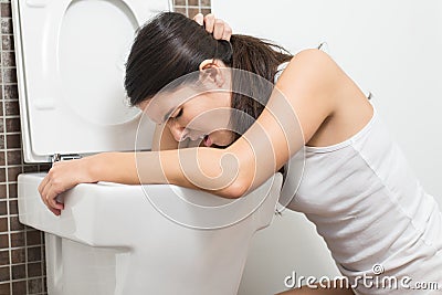 Woman vomiting into the toilet bowl