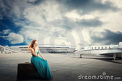 Woman waiting flight departure sitting on suitcase talking on phone Stock Photo