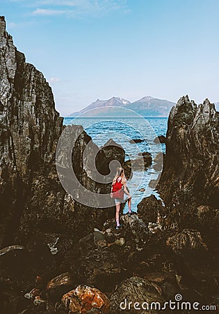 Woman walking alone looking at sea rocks coast in Norway enjoying ocean view Stock Photo