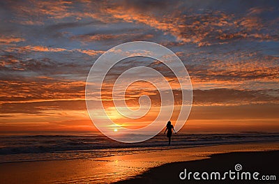 Woman walking on the beach at sunrise. Stock Photo